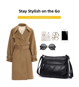 Flat lay of black multi-zippered crossbody bag with accessories and a trench coat