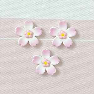 Close-up of pink cherry blossom resin charms with yellow stamens for DIY crafts