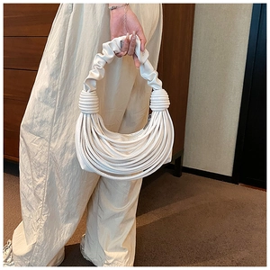 Detail of white pleated handbag strap and multi-layer curved faux leather design
