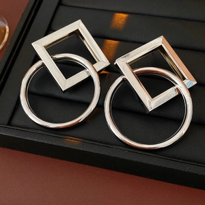 Détail de boucles d'oreilles géométriques en argent avec formes en métal entrelacées