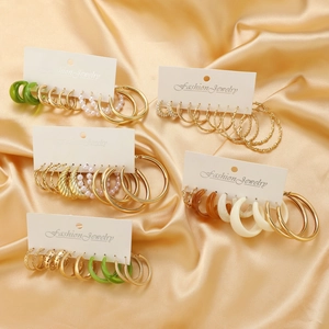 Elegant twisted hoop earring set with gold metal and green faux pearls on satin background