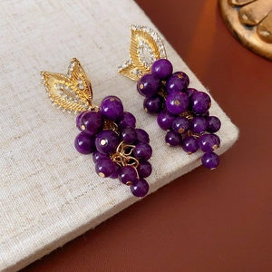 Close-up of vintage purple beaded grape earrings with gold rhinestone leaves