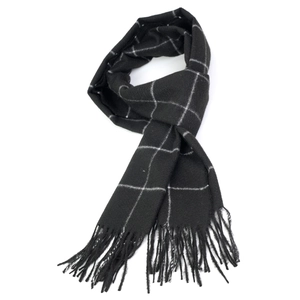 Detail of soft black and white plaid scarf with fringe tassels on white background
