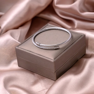Macro shot of silver cable twisted cuff bracelet on champagne silk and jewelry box