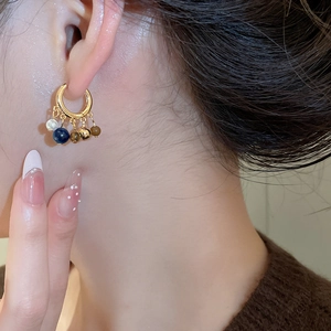 Close-up of 18k gold plated hoop earrings featuring tiger eye beads and pearls on model