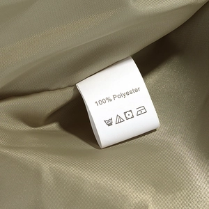Close-up of 100% polyester fabric care label on a golden brown quilted jacket