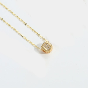Detail of gold square pendant necklace with letter B and sparkling crystal inlay