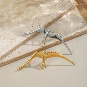 Elegant gold and silver swallow bird rings displayed on minimalist stone texture background