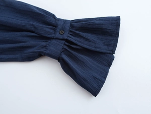 Detailed close-up of dark blue ruffle cuffs with buttons and pleated fabric texture