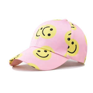 Detail view of pink twill baseball cap featuring yellow smiley face patterns and street style