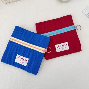 Detail view of small quilted cosmetic pouches with contrast zippers and metal ring pulls