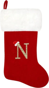 Detail of red velvet Christmas stocking with white faux fur cuff and gold glitter letter N