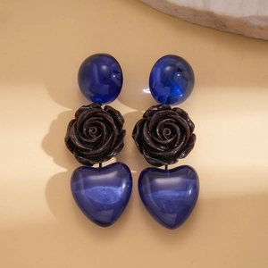 Détail de boucles d'oreilles avec rose en résine marron et cœur bleu transparent