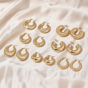 Collection of golden stainless steel hoop earrings in various textured designs on silk