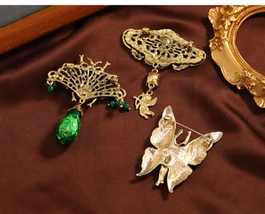 Detail of vintage emerald brooches showing back pin closure and antique gold metal texture