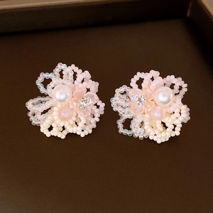 Detailed close-up of handmade beaded leaf flower earrings with pearls and crystals