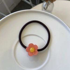 Élastique à cheveux fleur rose sur assiette en céramique avec ruban marron