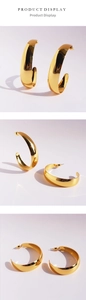 Detailed view of large gold-tone C-shape hoop earrings with a mirror polished finish
