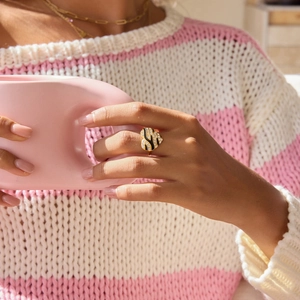 Close-up of heart-shaped gold ring with black enamel animal pattern and pavé zircons