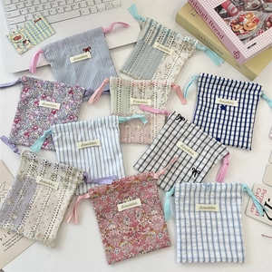 Gros plan sur des sacs de rangement en coton à fleurs et rayures avec cordon de serrage