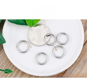 Detailed view of silver stainless steel jump rings next to a coin for size reference