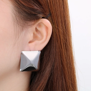 Macro view of large geometric square stud earrings in polished silver stainless steel