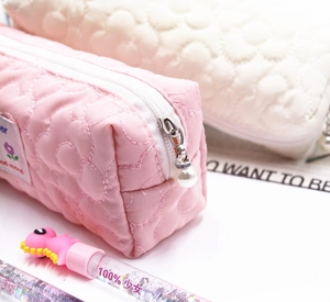 Close-up of quilted floral pencil case with soft texture and elegant pearl zipper charm