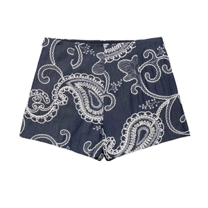 Detailed close-up of dark blue denim shorts with intricate white paisley embroidery