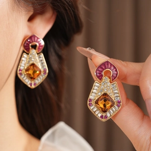 Detail of vintage gold earrings with purple enamel, amber stones, and clear diamonds
