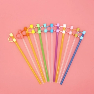 Set of 12 colorful silicone straws with dust caps arranged on pink background
