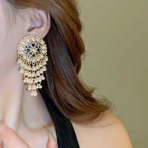 Close-up of bohemian hollow teardrop earrings with cascading pearls on a model