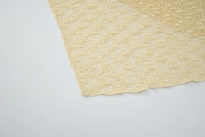 Detail shot of pale yellow mesh knit fabric with intricate openwork floral patterns