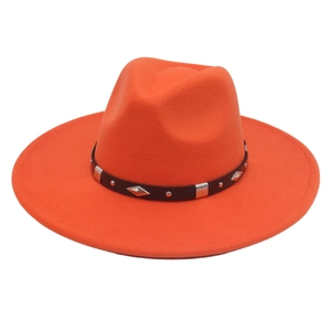 Detail of orange fedora hat featuring black band with silver rivets and diamond metal studs