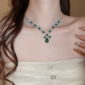 Close-up of model wearing luxury silver necklace with pear-cut emerald and zircon gems