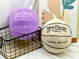 Detailed view of purple and beige basketball plush pillows with embroidered text
