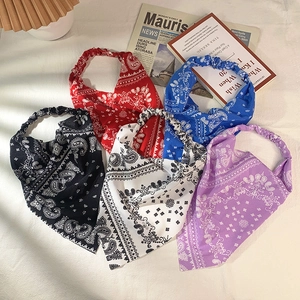 Flat lay of five paisley cotton triangle bandanas in black, red, blue, white, and purple