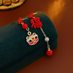 Detail view of lion dance and Fu character earrings with pearls on blue velvet stand