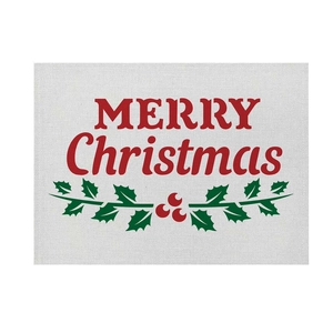 Close-up of linen Christmas placemat with red Merry Christmas print and holly leaves