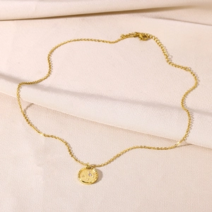 Close-up of 18K gold zodiac pendant necklace resting on elegant beige silk fabric