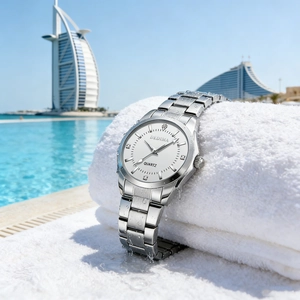 Waterproof silver ladies quartz watch with white dial shown against a luxury poolside resort