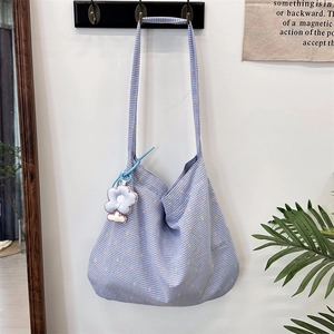 Detailed view of blue checkered shoulder bag with light blue beaded flower charm hanging