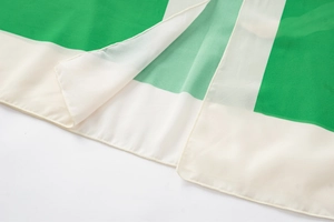 Close-up of fine edge stitching and texture on a green and beige floral one-piece swimsuit