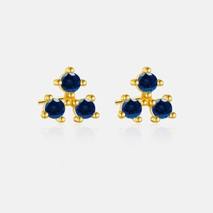 Detail view of gold stud earrings featuring three blue round stones in a clover design