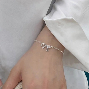 Macro shot of a S925 sterling silver bowknot charm chain bracelet on a woman's wrist
