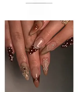 Détail de faux ongles amande avec nœuds 3D, perles et motifs à pois marron chocolat