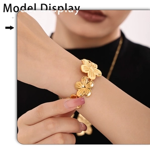 Detail of a gold floral open cuff bracelet with sunburst petal textures on a model wrist