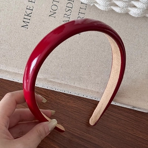 Serre-tête en cuir PU bordeaux brillant avec doublure antidérapante sur fond en bois