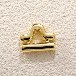 Macro shot of 3D golden Libra zodiac charm with a polished finish on a stone surface