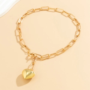 Close-up of golden paperclip link necklace featuring a minimalist heart pendant