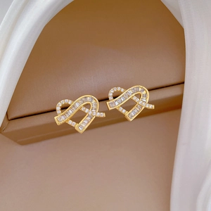 Detailed macro view of golden heart earrings with sparkling cubic zirconia on silk
